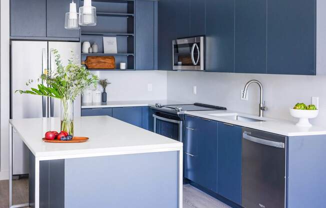 a kitchen with white counters and blue cabinets and a sink at The Lively, New Jersey