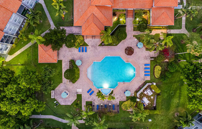 A swimming pool surrounded by a grassy area and trees.