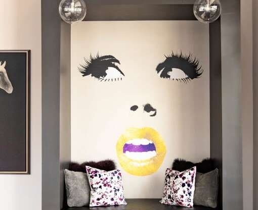 a wall with a mural of a face and a bench with pillows