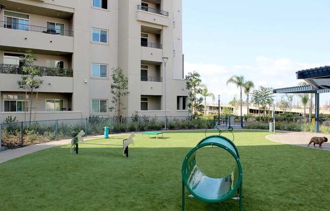 A playground with a green slide in front of a white apartment building.