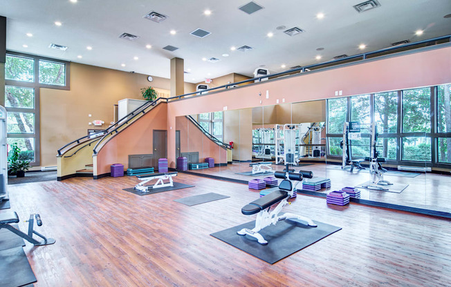 a spacious fitness room with yoga mats and exercise equipment and large windows