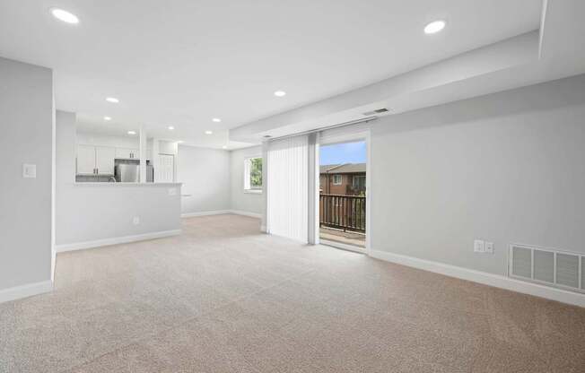 A spacious living room with a sliding glass door leading to a balcony.