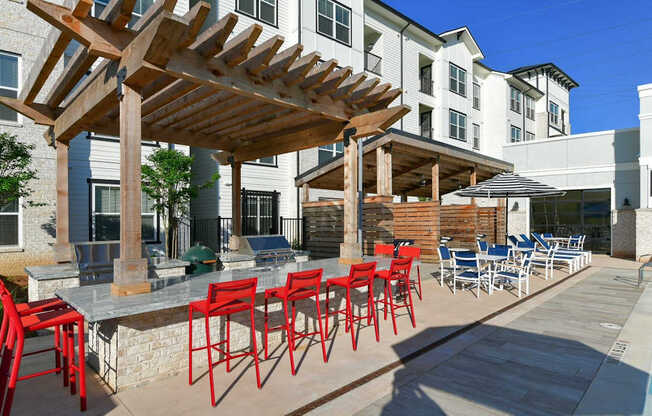 a patio with red chairs and a table with chairs