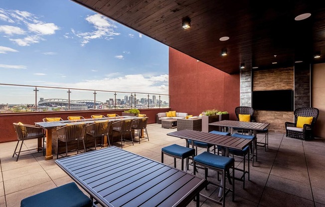 a rooftop patio with tables and chairs and a view of the city
