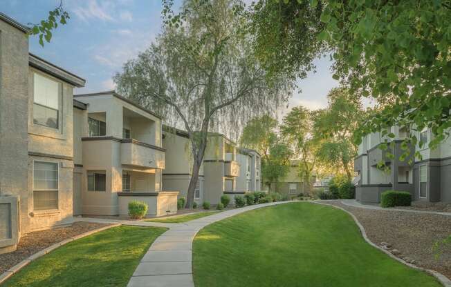 an exterior view of an apartment complex with green grass and trees