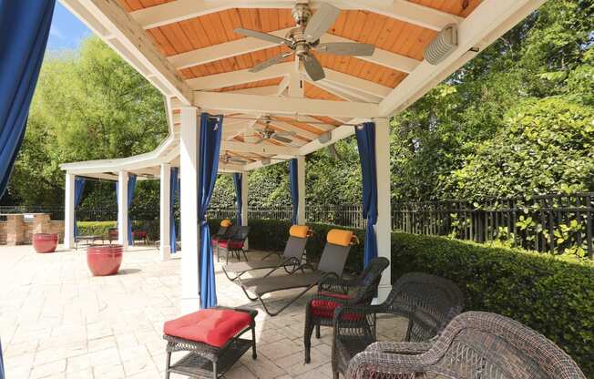 a covered patio with wicker chairs and a ceiling fan