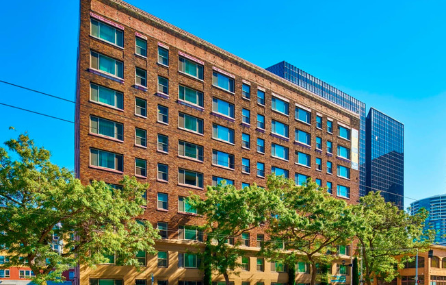 A large brick building with many windows and trees in front.