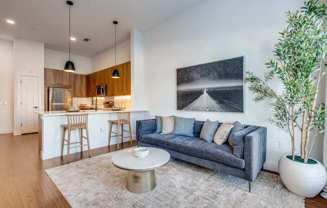 A modern living room with a grey sofa, a coffee table, and a large painting on the wall.