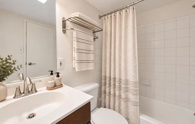 A white bathroom with a toilet, sink, and bathtub.