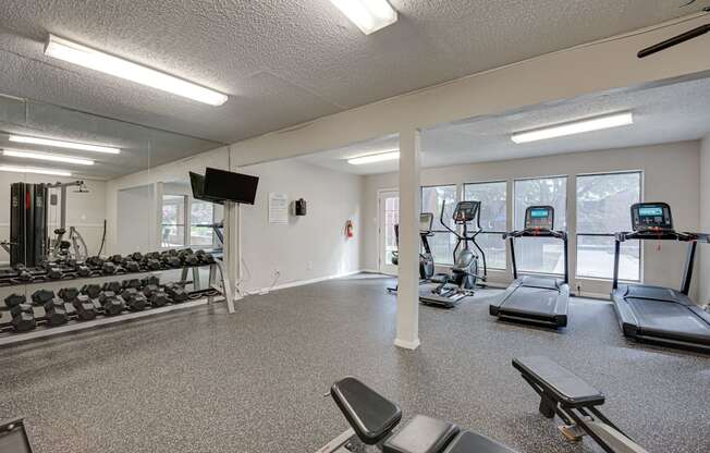 a gym with treadmills and other exercise equipment and windows