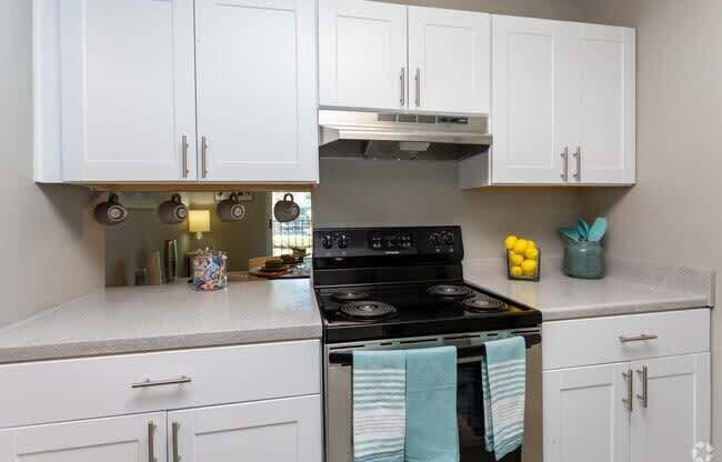 A kitchen with white cabinets and a black stove top.