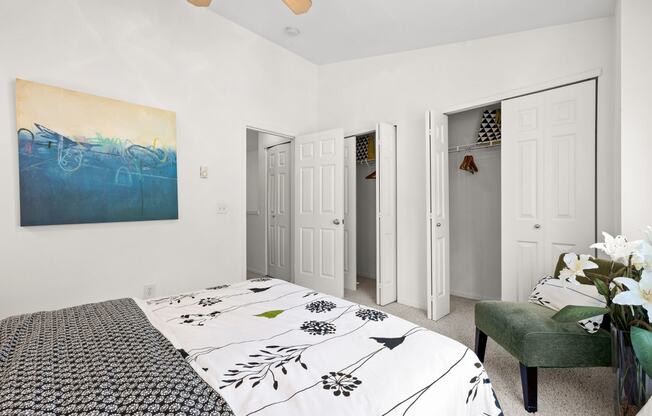 a bedroom with white walls and a white bedspread with black and white flowers on it