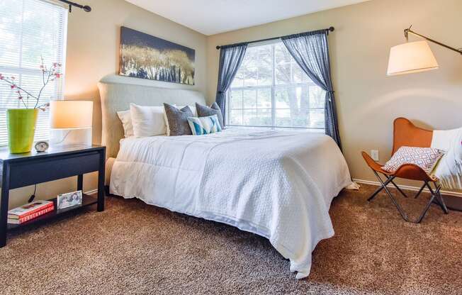 a bedroom with a large bed and a chair next to a window  at Riverset Apartments, Tennessee, 38103