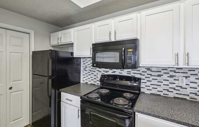 B1 floor plan kitchen with black appliances and white cabinets at Jefferson Creek Apartments in Irving, TX.