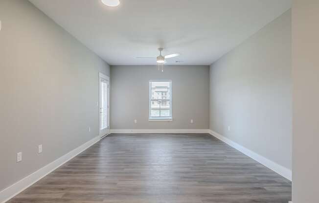 an empty living room with wood floors and a window