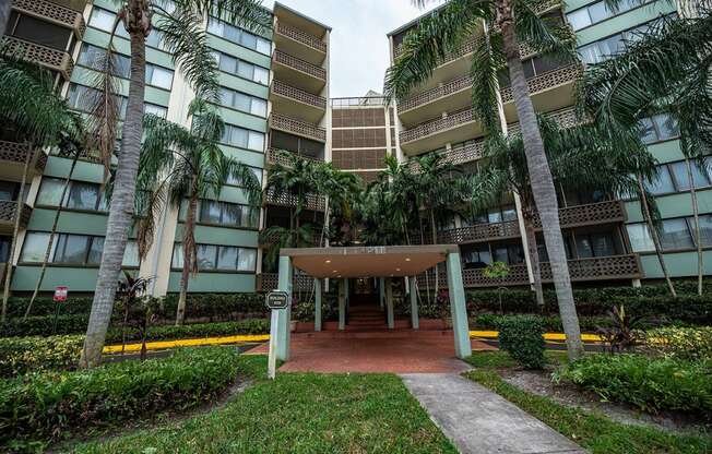 an entrance to an apartment building with palm trees at Fairways of Inverrary, Lauderhill, Florida