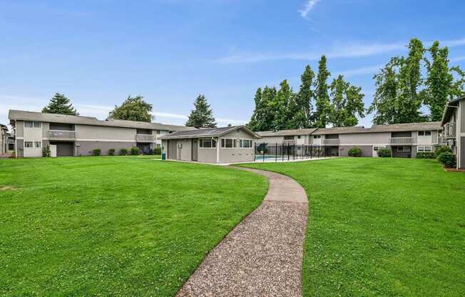 A grassy area with a concrete walkway leading to a building.