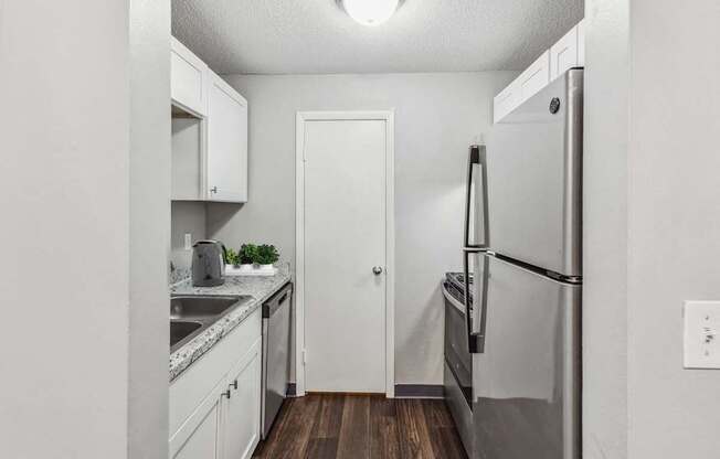 A kitchen with a refrigerator, sink, and cabinets.