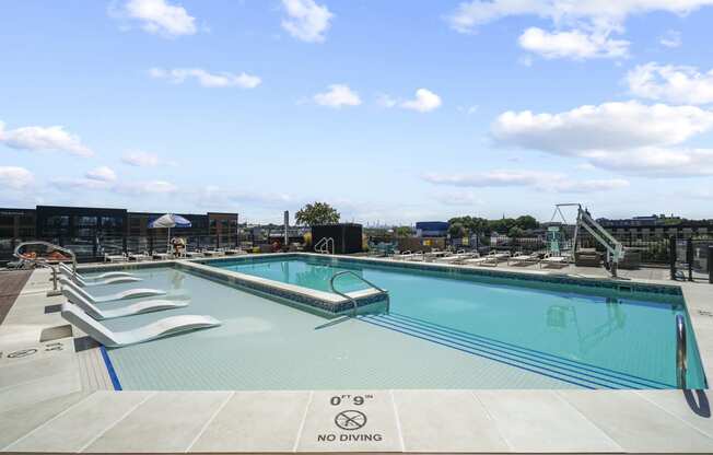 a swimming pool on the rooftop of a hotel with a city in the background