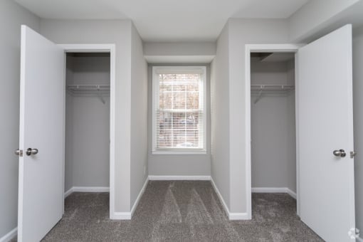 an empty bedroom with two closets and a window