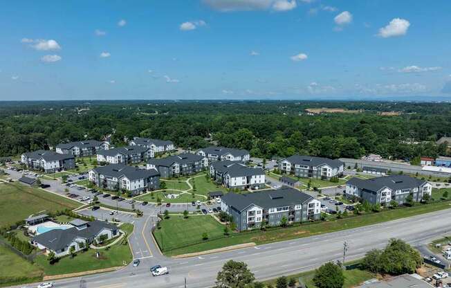 A large apartment complex is surrounded by trees and a road.