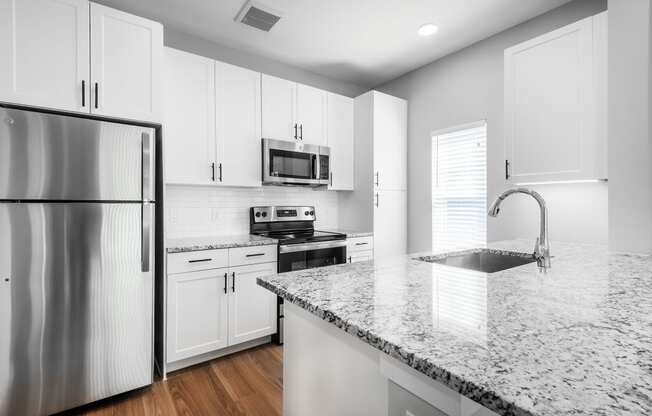 a kitchen with white cabinets and granite counter tops and a stainless steel refrigerator