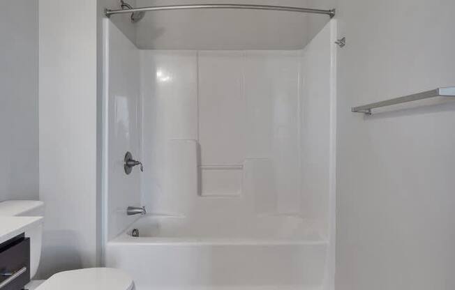 A white toilet sits next to a walk-in shower in a bathroom.