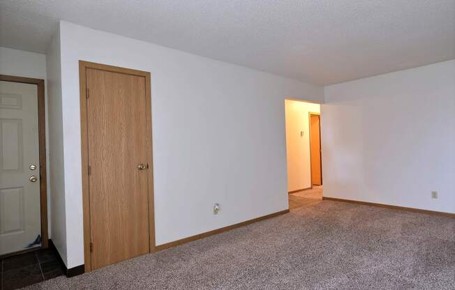 A living room of an empty apartment with a door to the hallway at Parkwest Gardens, 58078 