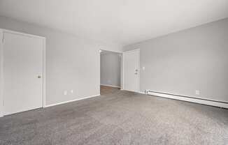 A room with a carpeted floor and two doors.