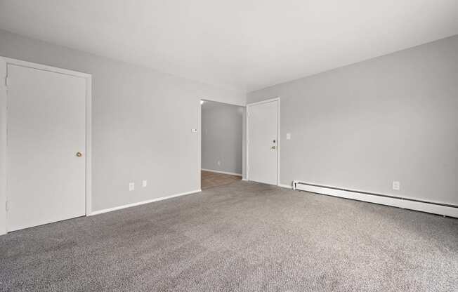 A room with a carpeted floor and two doors.