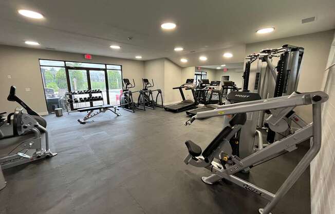 A gym with a variety of exercise equipment including treadmills, stationary bikes, and weight machines.