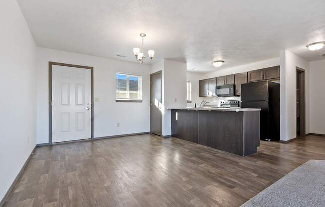 A spacious living room with a kitchen area in the background.