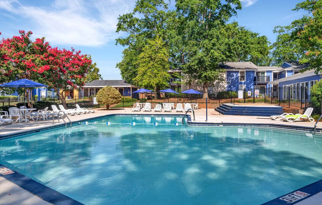 a swimming pool with chairs and umbrellas next to a building