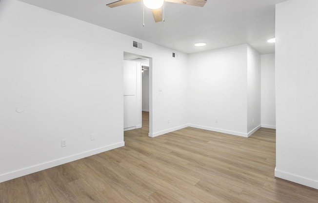 an empty living room with white walls and a ceiling fan