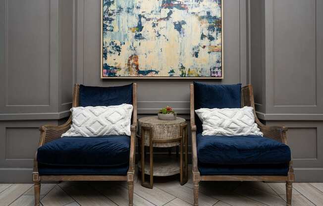 Two chairs with blue cushions and a small table between them.