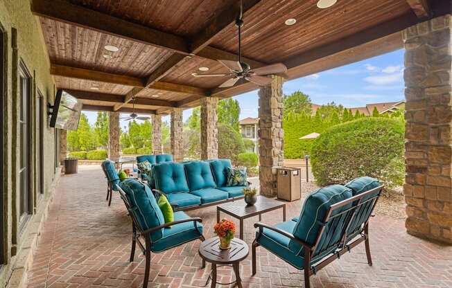a covered patio with blue couches and chairs