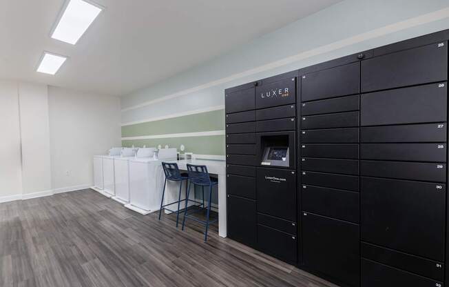 A room with a desk and chairs in front of a wall of lockers.