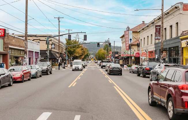 A street scene with cars parked on the side of the road and a few moving cars.