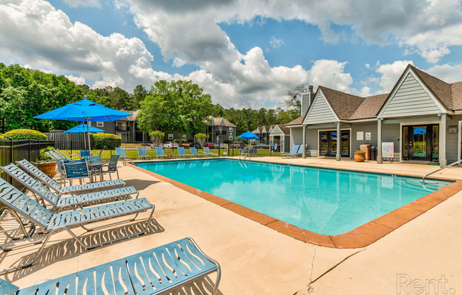 our resort style swimming pool is surrounded by lounge chairs and umbrellas