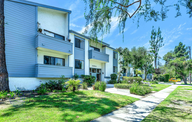 a white and grey apartment building with a sidewalk in front of it