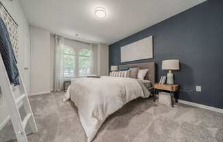 A bedroom with a large bed and a window with curtains.