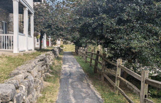 a dirt path next to a wooden fence and a house