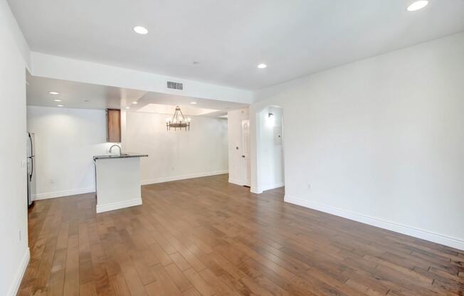 an empty living room with white walls and wood flooring