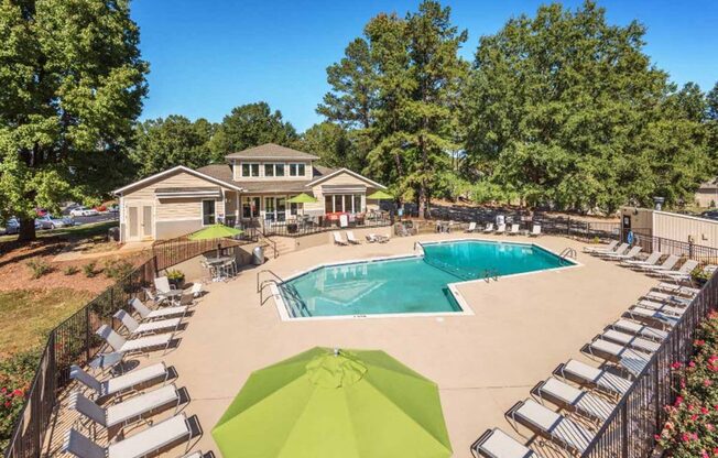 a swimming pool with chairs and umbrellas in front of a house