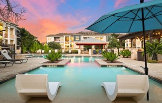 a swimming pool with two white chairs and an umbrella