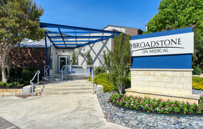 a white building with a blue awning and a sign that reads broadstone on m