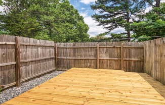 a backyard with a wooden deck and a wooden fence