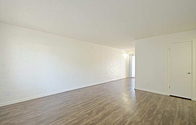 an empty living room with white walls and wood flooring