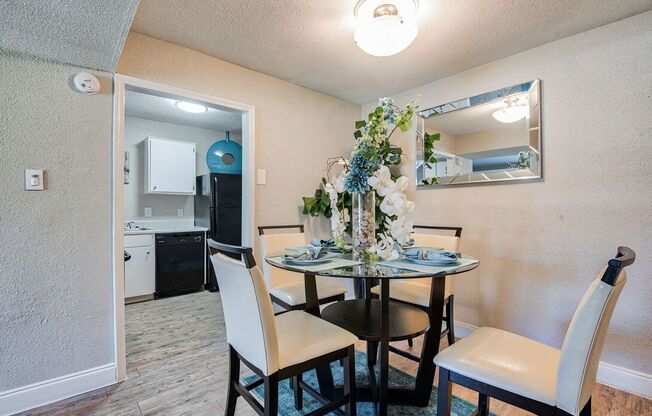 A dining room with a table set for two and a mirror above it.