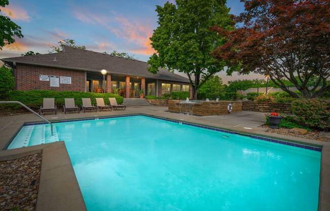 A swimming pool in front of a house with trees around.